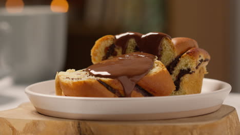 close up of melted chocolate sauce poured onto chocolate babka bun on plate