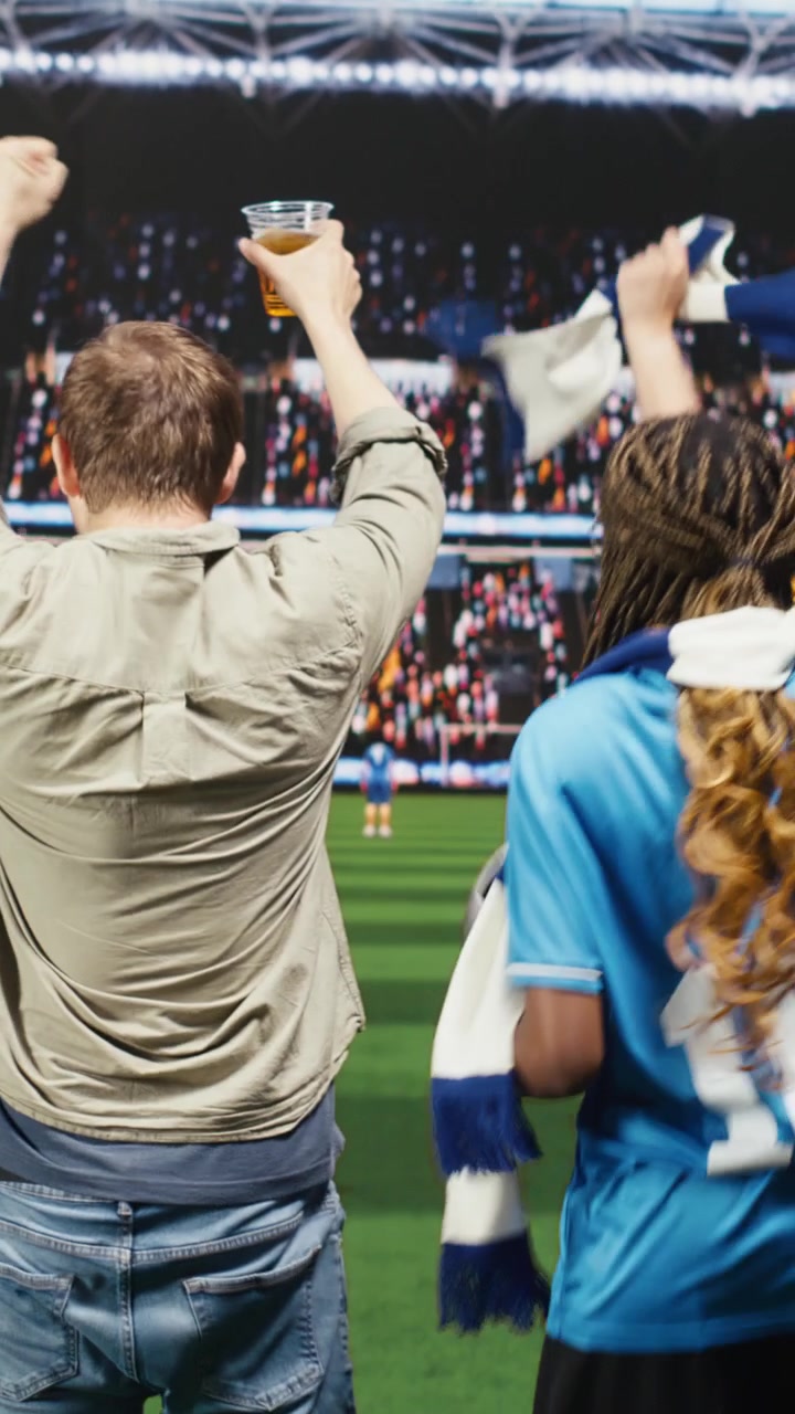 Video vertical: Aficionados al fútbol ven el partido en casa desde el sofá con tecnología de televisión inmersiva
