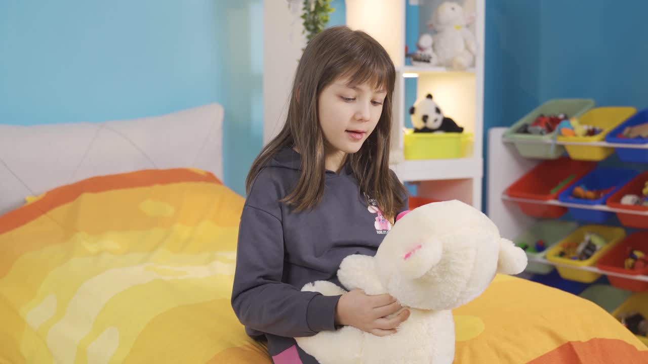 방에 혼자 있는 작은 소녀는 테디 베어와 얘기하고 친구를 사귀습니다.
