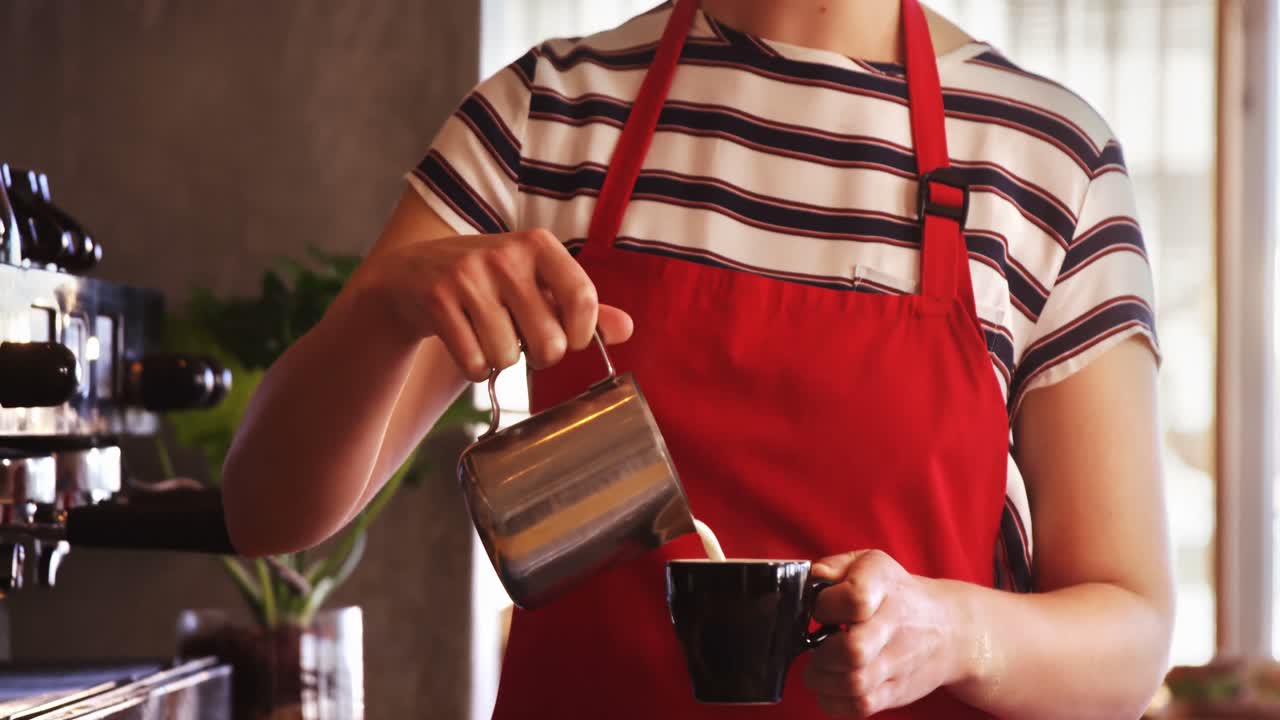 Waitress making cup of coffee at counter in caf&Atilde;&copy;