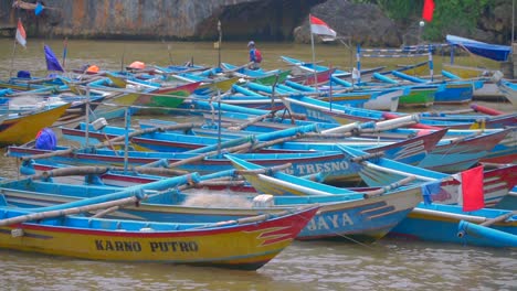 outrigger fishing boats floating in harbor with fisherman anchoring canoe with rope, indonesia