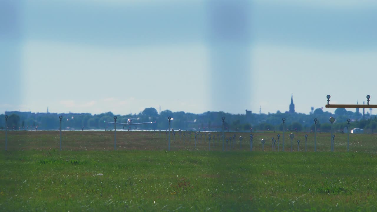 프로펠러 엔진이 장착된 작은 흰색 훈련 비행기는 화창한 여름날 공항 활주로에서 멀리서 중간 샷을 날립니다.