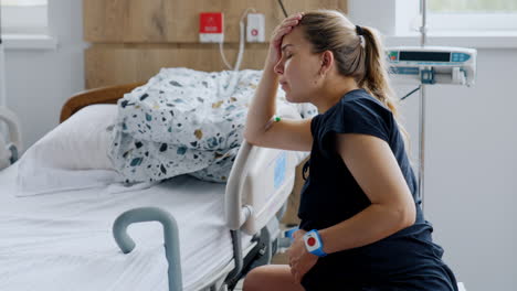 caucasian pregnant lady sits on the fit ball in hospital ward. woman has painful contractions and tries slow breathing.