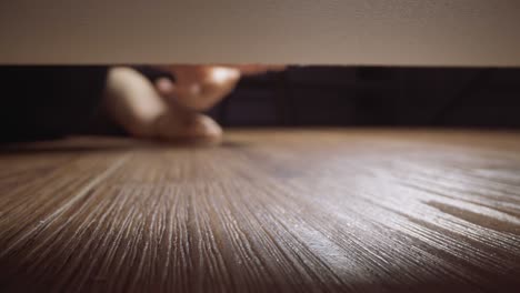 Woman takes gold ring rolled under sofa on wooden floor