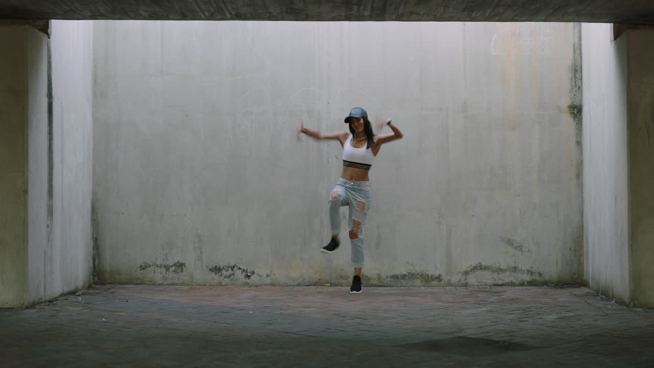mujer bailarina joven bailarina de calle de raza mixta realizando movimientos de hip hop de estilo libre disfrutando de la expresión de danza moderna practicando en un almacén grungy