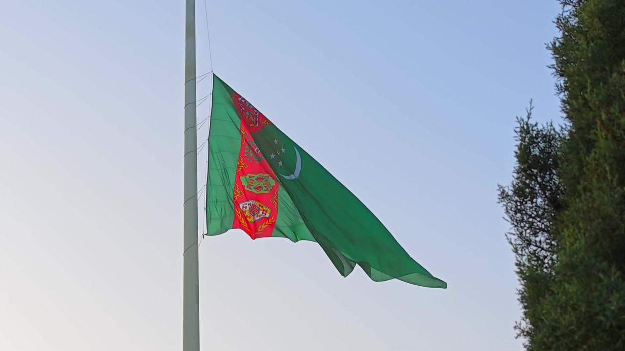 Bandera de Turkmenistán ondeando contra un cielo azul claro