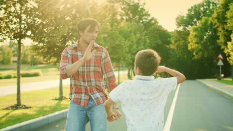 boy and man dancing in park. joyful father and son giving high five outdoors