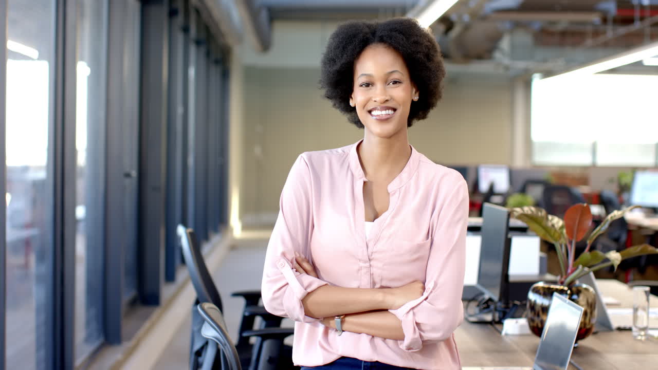 African american woman standing confidently with arms crossed in modern office