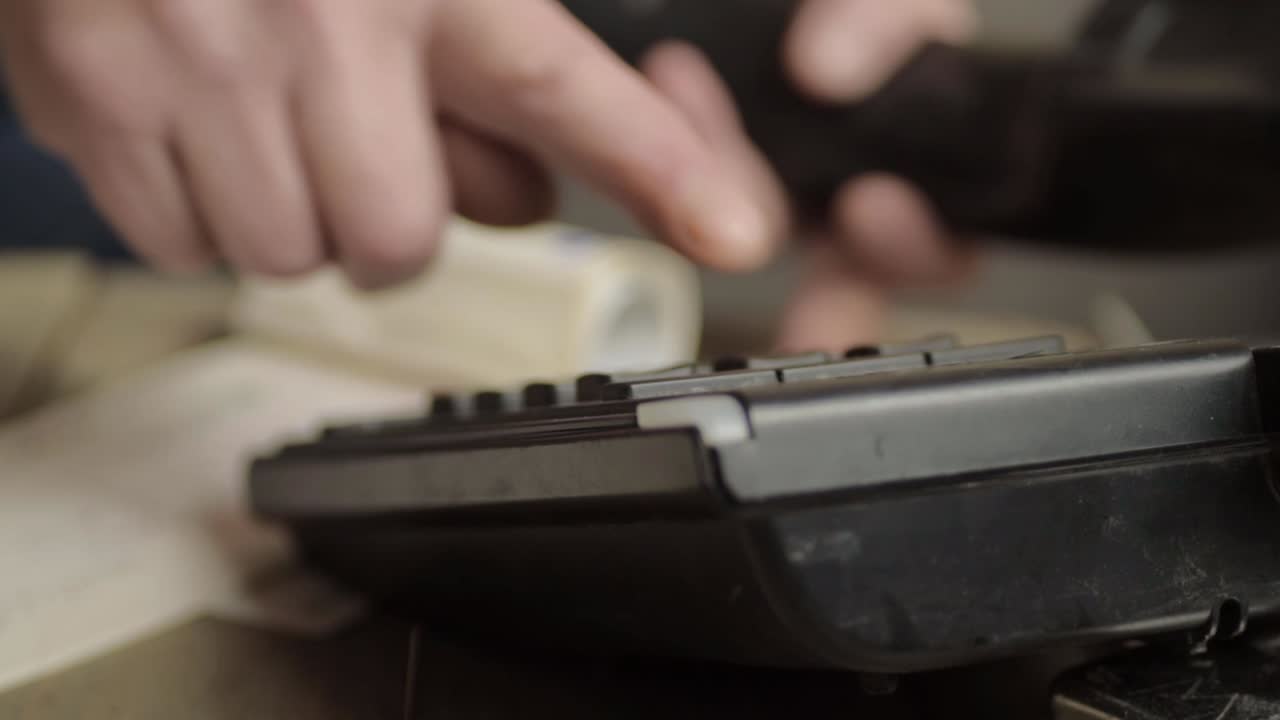 Hand making a call from desk phone