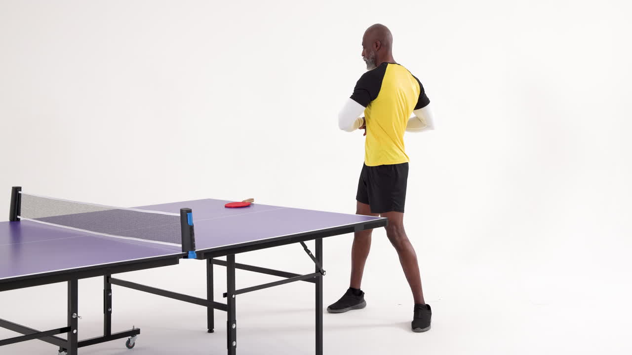Playing table tennis, african american man in sportswear standing by table with paddle