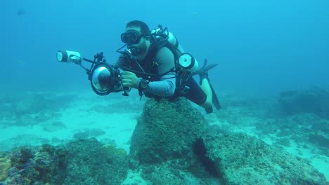 un video de un camarógrafo submarino que toma fotos de la vida marina en el océano con equipos y luces submarinos