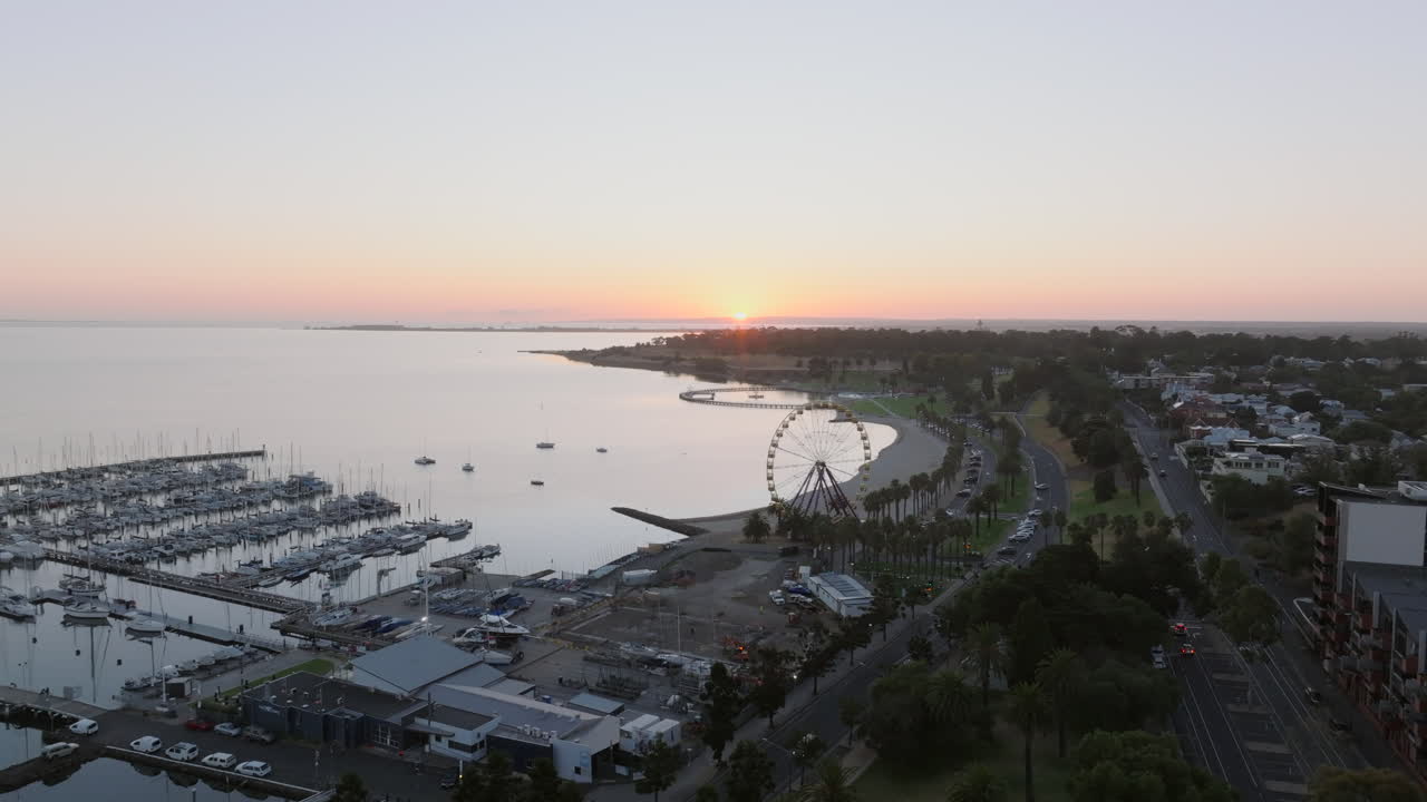 el sol se levanta en el aire sobre geelong, australia, en la playa este con la rueda gigante.