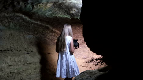 a lonely girl walks in a cave underground caves and tunnels girl tourist walks around the cave and examines it underground caves and tunnels