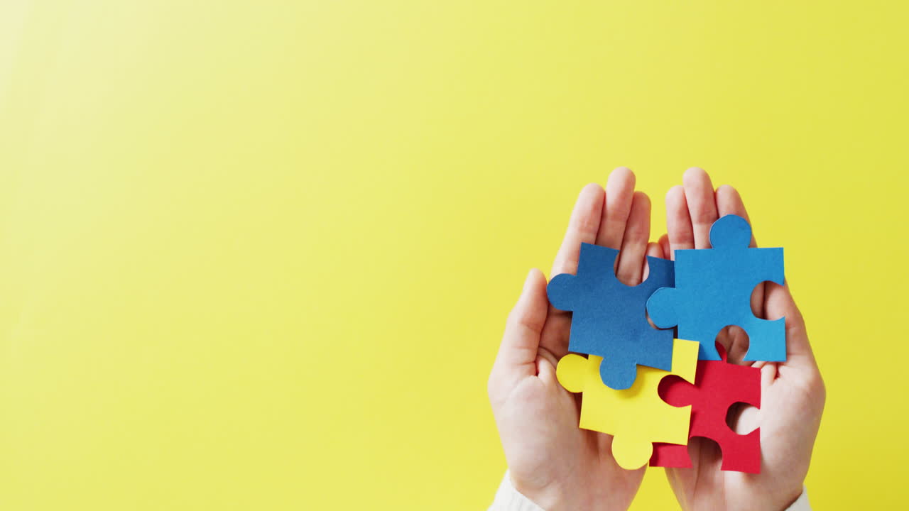 video de manos sosteniendo piezas de rompecabezas en fondo amarillo con espacio de copia