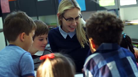 teacher helping schoolkids with their homework in classroom