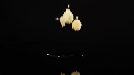 baby corn pieces dropping onto a reflective surface