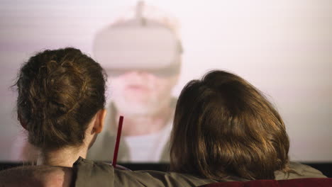 rear view of couple hugging sitting in the cinema while they watching a movie and talking 1