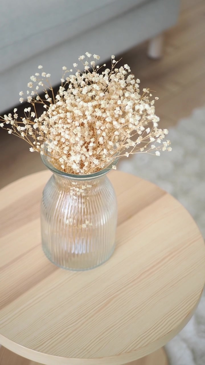 Fleurs de gypsophile séchées dans un vase en verre sur une table en bois