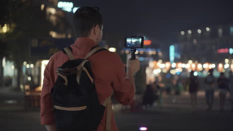 man filming a video in a city at night