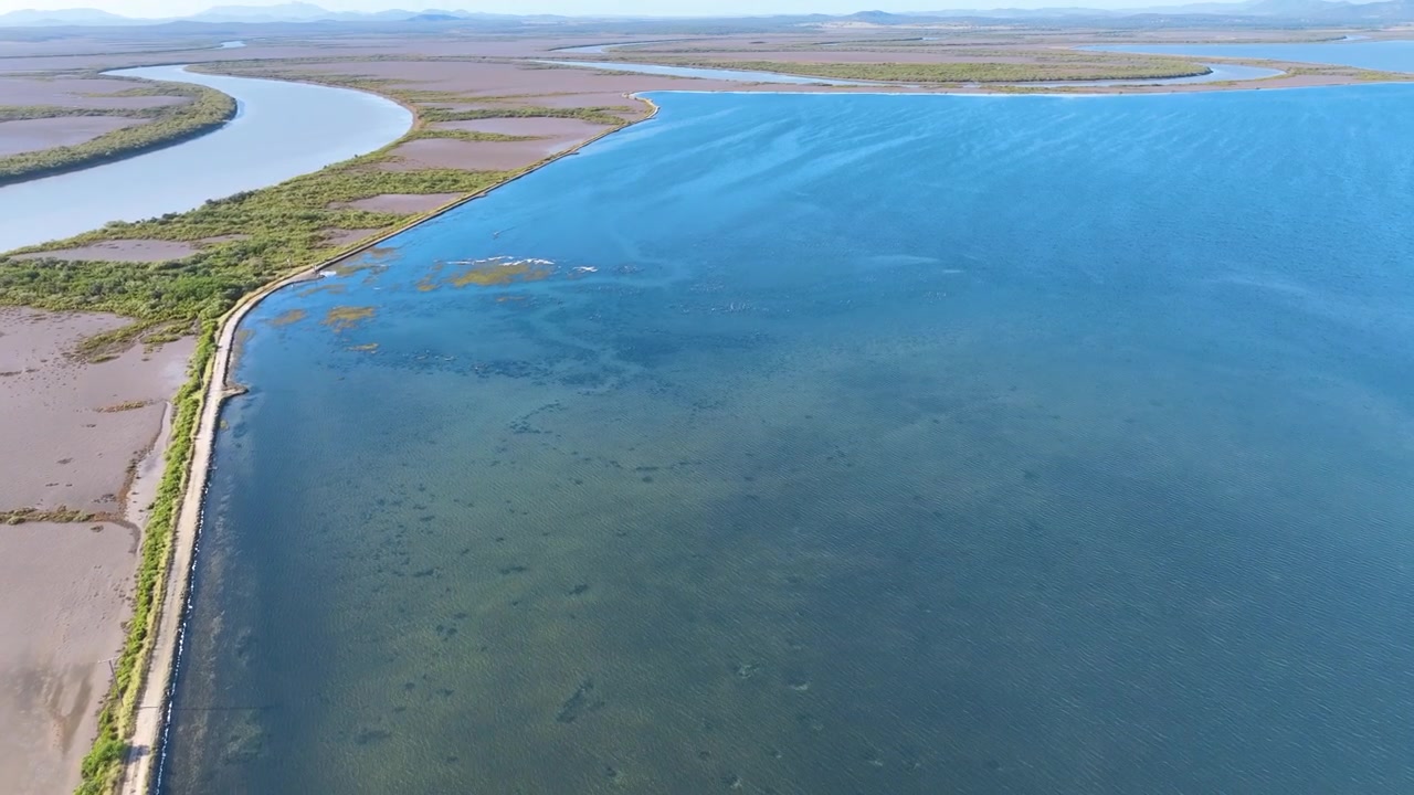 Imagens aéreas percorrem uma vasta variedade de ambientes usados para a produção de cristais de sal na área australiana de Port Alma. Lagos de cor barrenta transicionam através de vegetação exuberante para tanques de evaporação azul cobalto