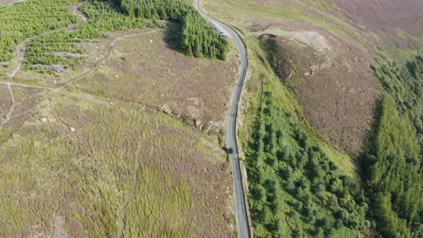 Draufsicht-Auf-Ein-Schwarzes-Auto,-Das-Entlang-Einer-Straße-In-Einem-Grünen-Wald-Entlang-Der-Wicklow-Mountains-Fährt