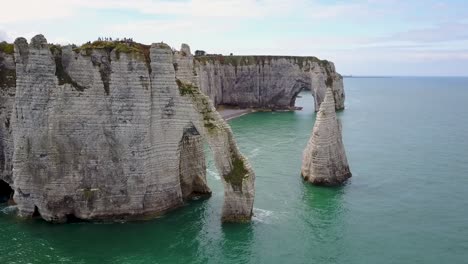 flying upward looking at the rocky arch of etretat in normandy