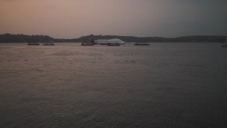 An-establishing-shot-overlooking-the-beautiful-Mahadayi-River-at-sunset,-in-the-distance-the-local-fishing-boats-and-vessels-remained-anchored-for-the-night,-Goa,-India