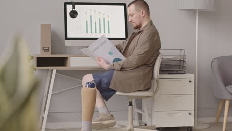 businessman with prosthetic leg reading annual report