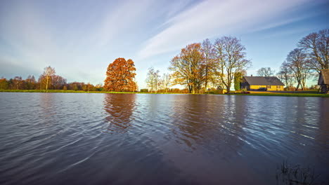 Calm-lake-and-small-wooden-home-with-changing-weather-conditions,-time-lapse