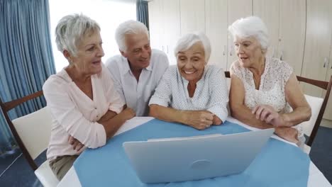 un anciano y una anciana usando una computadora portátil en un hogar de ancianos