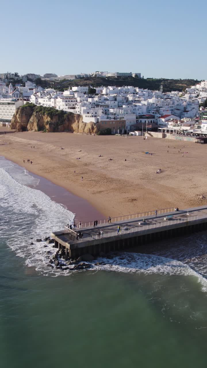 Scatto aereo verticale che cattura le sabbie dorate di Albufeira e il pittoresco molo in Algarve, Portogallo.