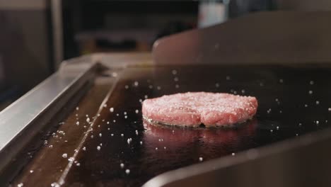 close up shot of raw beef cutlet for burger frying on electric commercial grill.