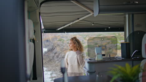 mujer positiva relajándose en una autocaravana mirando la belleza de la naturaleza. turista femenina rizada