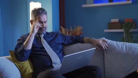 Thoughtful-businessman-resting-on-sofa-at-home-and-working-on-laptop.