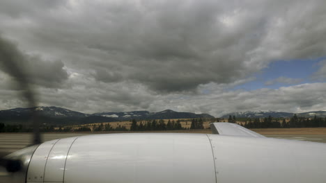 Wing-of-airplane-with-propeller-spinning-rapidly-while-plane-taxies-on-tarmac-under-cloudy-skies