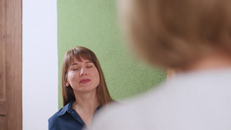 supportive listener in blue shirt focused on patient seated in calm therapy setting, showing attentive body language and facial expression, light green wall and soft tones emphasize warmth