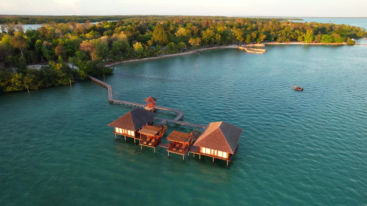 To eksotiske bungalows over vandet med terrasser til solbadning og lang mole, der forbinder villaerne med Leebong Island, Belitung Indonesien - Luftparallax