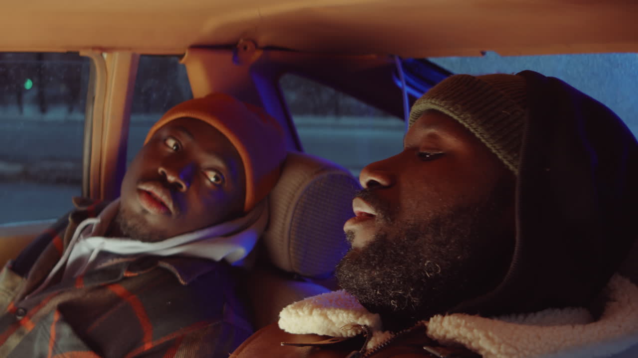 dos hombres negros hablando en el coche por la noche