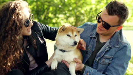 el marido y la esposa están besando a su mascota favorita, un lindo perro, luego lo acarician en la cabeza y se ríen, se divierten con los animales, aman a los cachorros y el concepto de juventud.