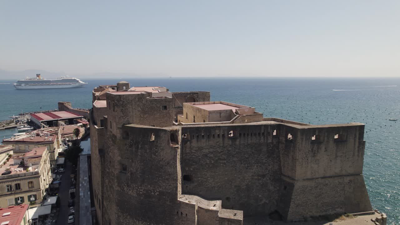 toma aérea de cierre del castel dell' ovo con un crucero que pasa al fondo