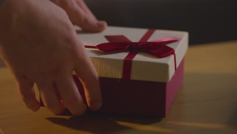 close up of man picking up romantic valentines present in gift wrapped box from table 1