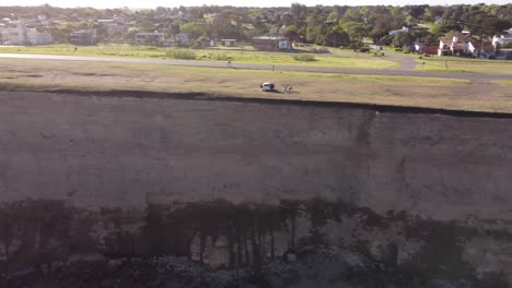 Cyclist-pedaling-along-panoramic-road-near-cliffs-Acantilados,-Mar-del-Plata-in-Argentina