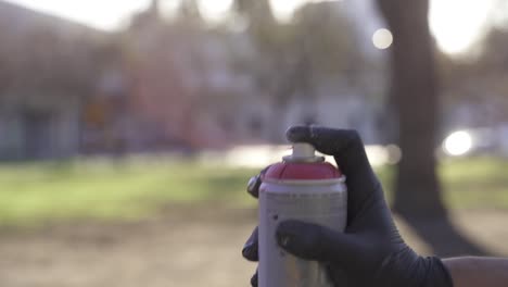 hand with black glove spraying paint in air