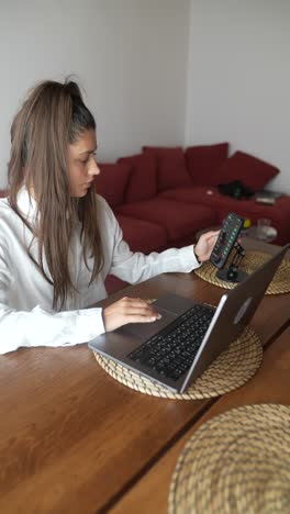 young woman working from home on her laptop and checking stock charts