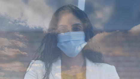 clouds in blue sky against indian woman wearing facemask using hands sanitizer