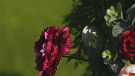 red artificial flower waving in wind against green leaves