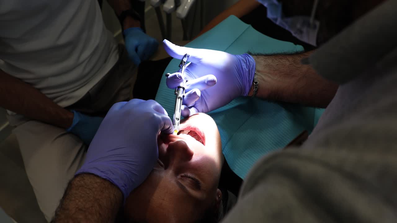 Dentista che somministra anestesia a un paziente durante una procedura dentale.