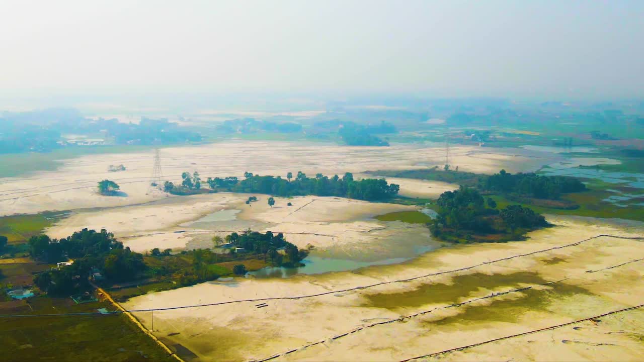 Aerial view of sandy rural plot area with trees in Bangladesh. Drone flying backward