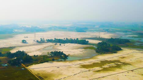 aerial view of sandy rural plot area with trees in bangladesh. drone flying backward