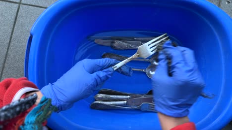 washing silverware in a blue bowl